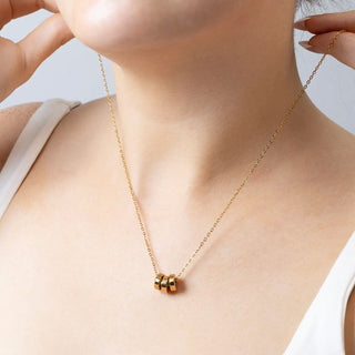 Gold necklace with a spacer bead on a person wearing a white top against a light background