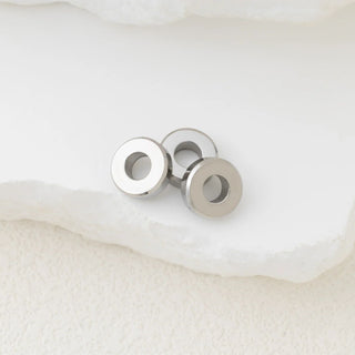 Silver spacer beads on a white stone background