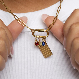 Gold necklace with charms held by hands against a white background