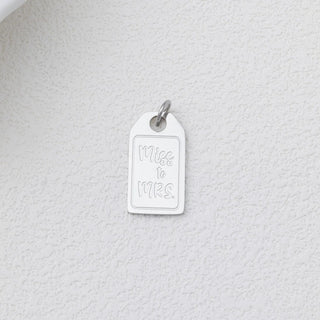 Silver 'Miss to Mrs.' charm on a textured white background