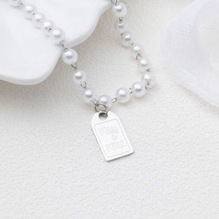 Pearl necklace with a silver tag on a white background
