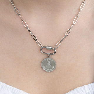 Silver necklace with a pendant on a person wearing a white top