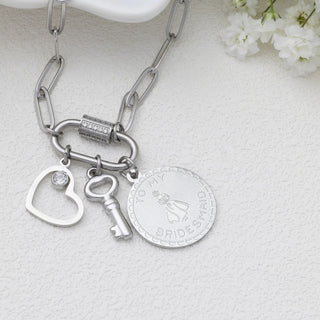 Silver chain bracelet with heart, key, and round charm on a light background