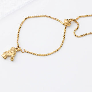 Gold bracelet with a roller skate charm on a white background