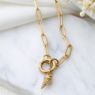 Gold chain necklace with a ice cream-shaped pendant on a white marble surface.