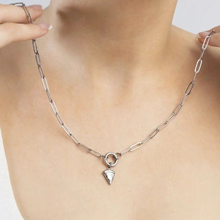Silver necklace with a pendant on a person's neck against a neutral background