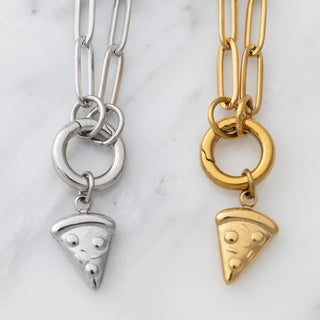 Two pizza-shaped charms on chain necklaces, one silver and one gold, on a marble background.
