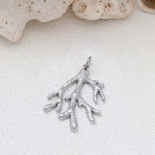 Silver coral pendant on a sandy background