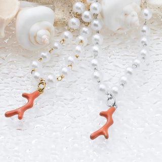 Pearl necklace with coral branch pendants on a textured white surface
