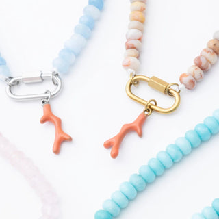 Three beaded necklaces with coral branch charms on a white background