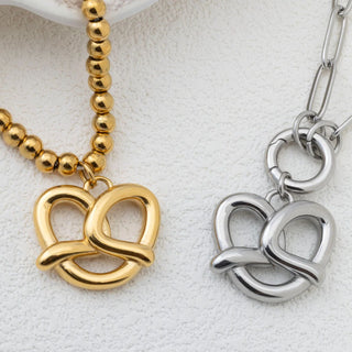 Gold and silver pretzel pendants on a textured white background
