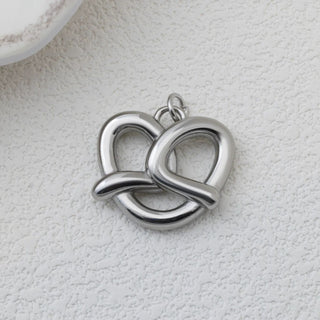 Silver pretzel pendant on a textured white surface