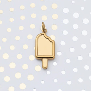 Gold popsicle charm on a polka dot background