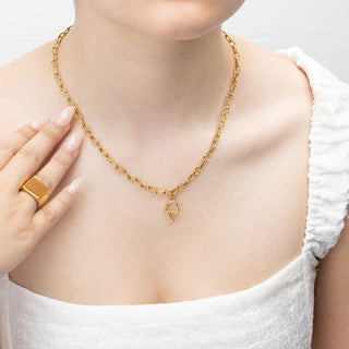 Gold necklace with an ice cream pendant worn by a person in a white top.
