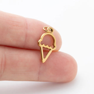 Gold ice cream cone-shaped pendant held between fingers on a white background