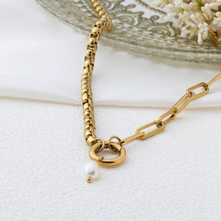 Gold chain necklace with a pearl pendant on a white surface