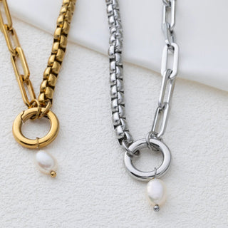 Two chain necklaces with pearl pendants on a light background