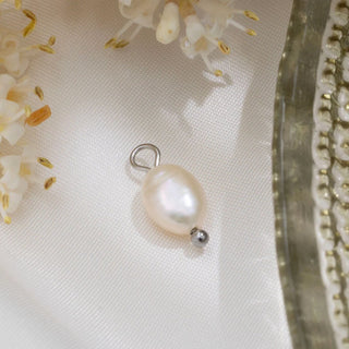 Pearl charm on a white fabric background with floral elements
