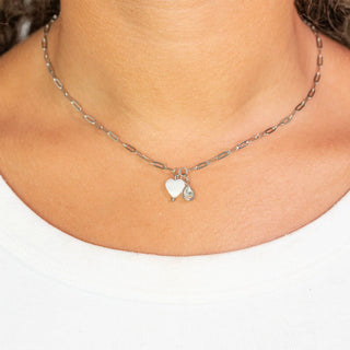 Necklace with heart-shaped charms worn by a person on a white background