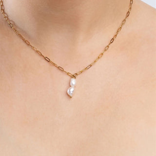 Gold chain necklace with pearl pendants on a person's neck