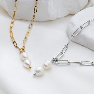 Two necklaces, one gold and one silver, on a white surface.