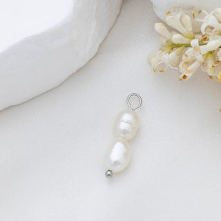 Pearl pendant on a white background with a soft focus on flowers