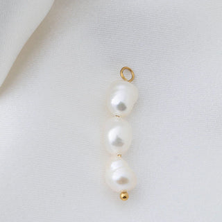 Pearl pendant with gold loop on a light gray background