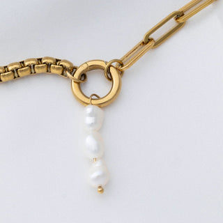 Gold chain necklace with a pearl pendant on a white background