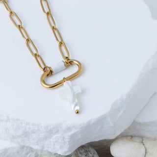 Gold chain necklace with a white pendant on a marble surface