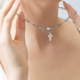 Silver chain necklace with a cross pendant on a person's neck