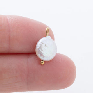 Pearl earring on a finger with a plain background