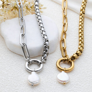 Two pearl-dangled chain necklaces, one silver and one gold, on a textured surface.