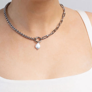 Necklace with a pearl pendant worn by a person on a plain background