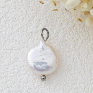 Pearl pendant with silver bail on a textured white surface