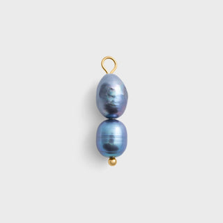 Two black pearls on a gold hook against a light gray background