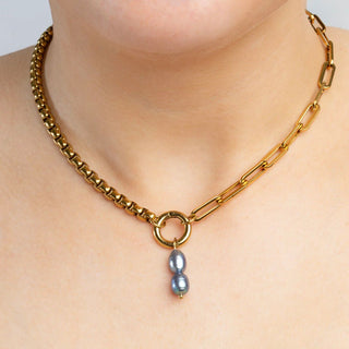 Gold necklace with a pearl pendant on a plain background
