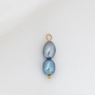 Two black pearls with gold clasps on a white background