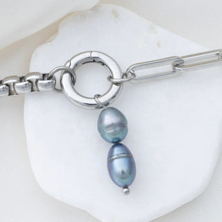 Silver bracelet with black pearls on a white shell background