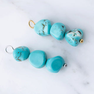 Turquoise beads with gold and silver clasps on a marble surface