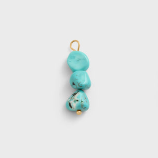 Turquoise stone pendant with gold accents on a light gray background