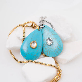 Turquoise teardrop pendants on gold and silver chains against a white background