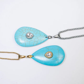 Two turquoise teardrop pendants on gold and silver chains against a white background