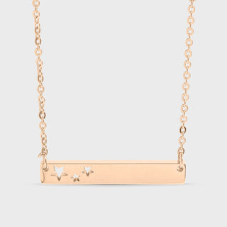 Rose gold necklace with star-shaped pendants on a light gray background