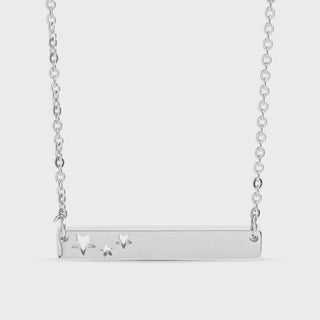 Silver necklace with star pendants on a light gray background