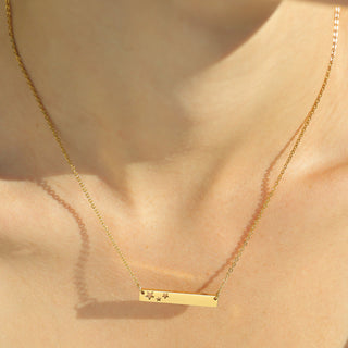 Gold necklace with a bar pendant featuring star cutouts