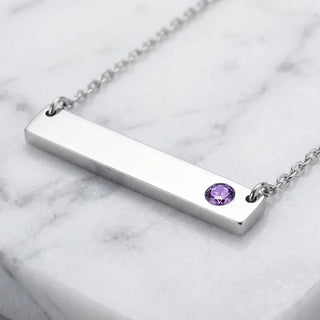 Silver bar necklace with a purple gemstone on a marble background
