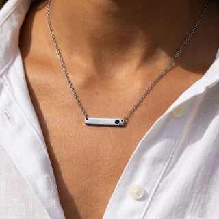 Necklace with a bar pendant worn by a person in a white shirt