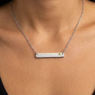 Silver bar necklace with a green gemstone on a person's neck